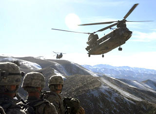 Three soldiers stand together in the mountains, waiting for two helicopters to land. Three soldiers stand together in the mountains, waiting for two helicopters to land.